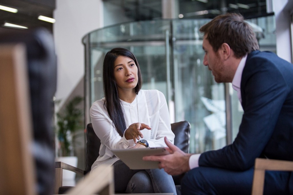 Businesswoman speaking with a colleague in a modern office.